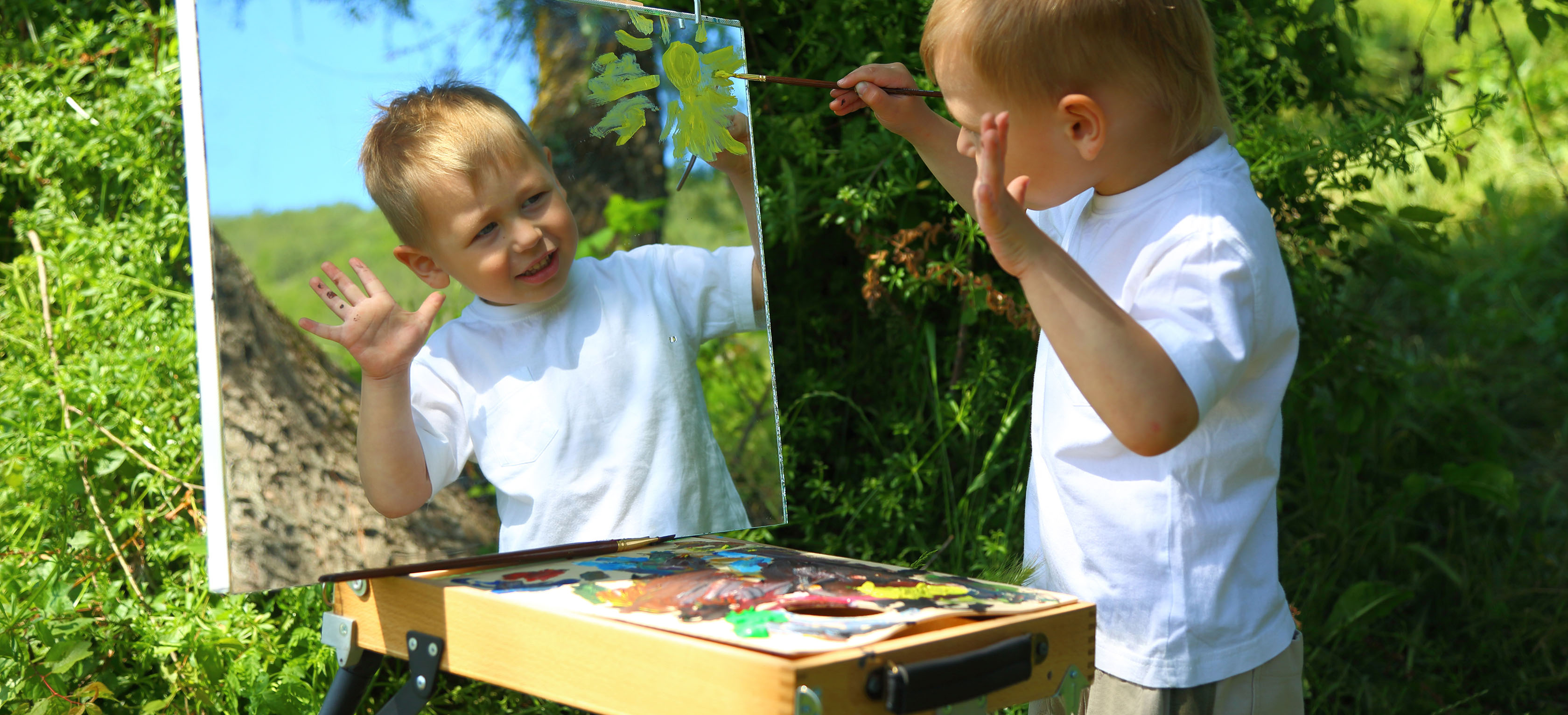 A young child painting outdoors